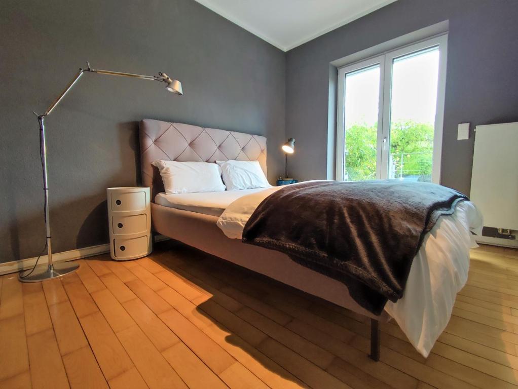 a bedroom with a bed with a lamp and a window at Zen Apartment - spacious - garden - kitchen in Karlsruhe