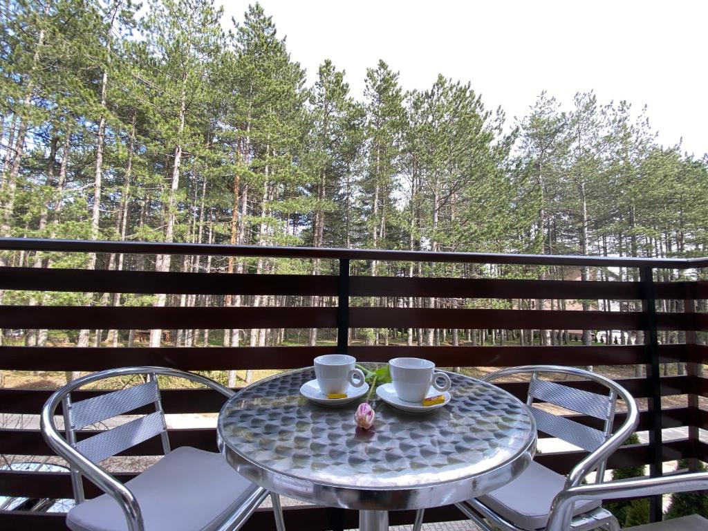 a table with two cups and chairs on a balcony at Miris tisine in Zlatibor