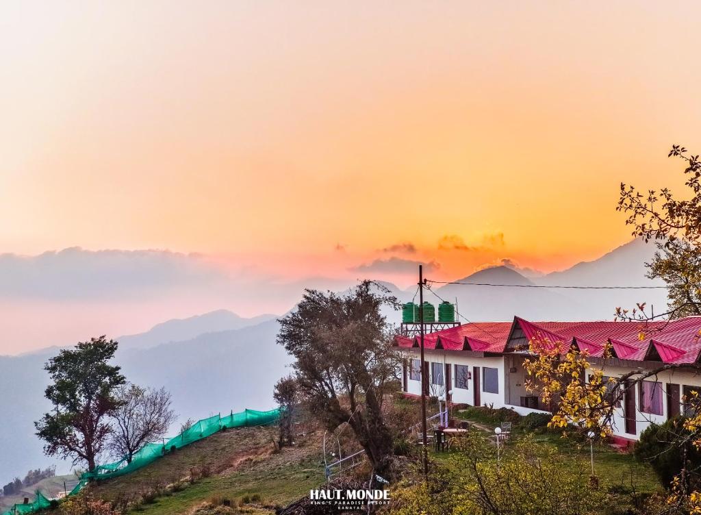 a building on a hill with a sunset in the background at Haut Monde King's Paradise Resort in Kanatal