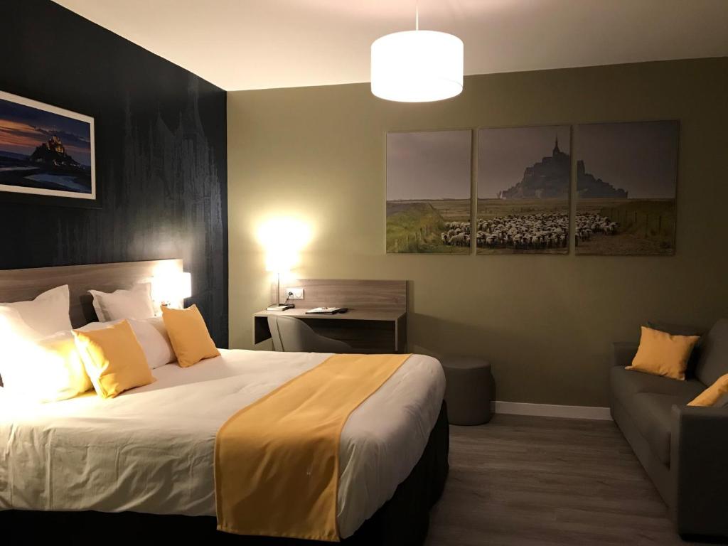 um quarto de hotel com uma cama e um sofá em Hôtel les 13 Assiettes em Le Val-Saint-Père