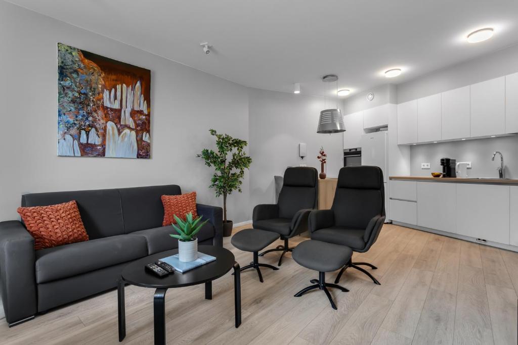 a living room with a couch and chairs and a kitchen at Tower Apartments in Reykjavík