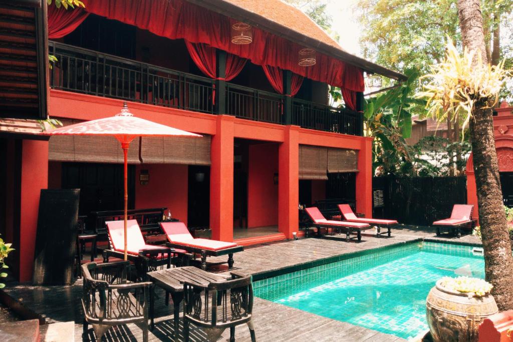 un complexe avec une piscine entourée de chaises et d'un parasol dans l'établissement Tri Yaan Na Ros Colonial House, à Chiang Mai