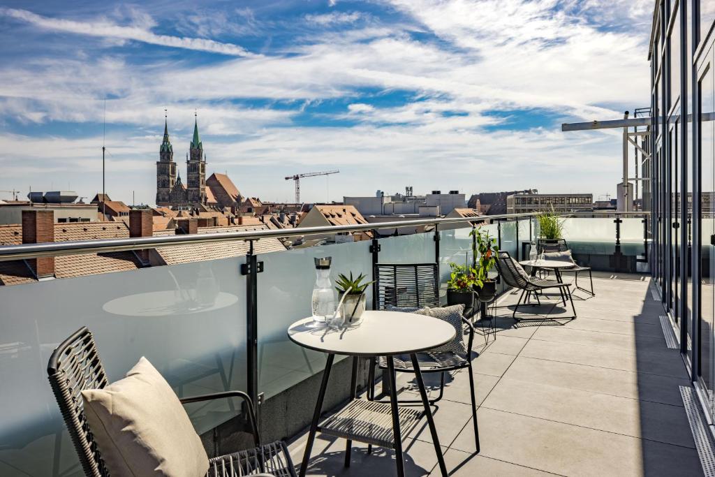 a balcony with tables and chairs and a view of a city at Luxus Penthouse über den Dächern von Nürnberg in Nuremberg