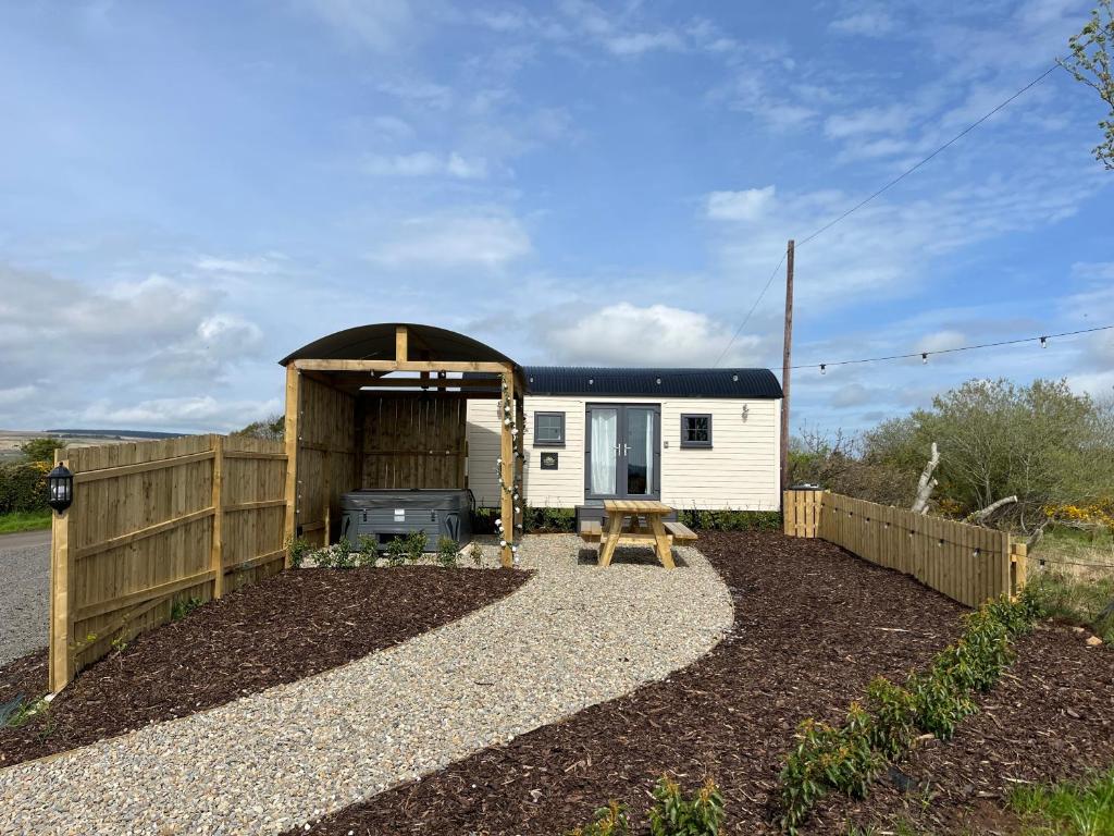 a small white caravan with a shed and a grill at Redfox Shepherds hut and private hot tub in Ballynameen