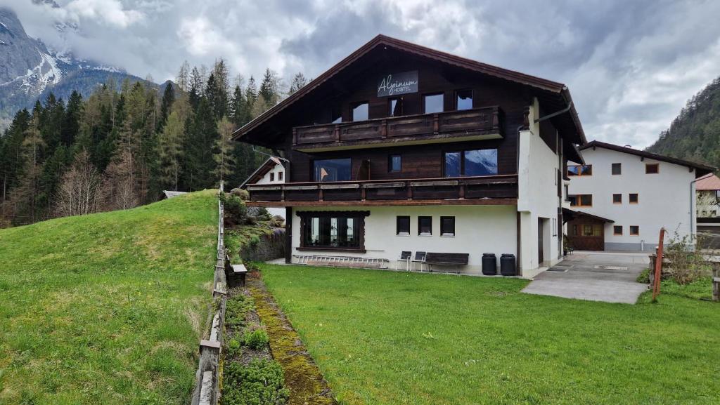 a large house on a hill with a grass yard at Alpinum Hostel in Biberwier