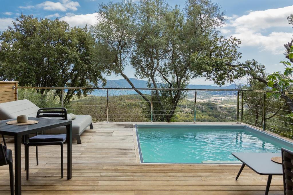 a patio with a pool and a table and chairs at SWIM LODGE HOTEL Piscine privée ou Jacuzzi privé in Porto-Vecchio