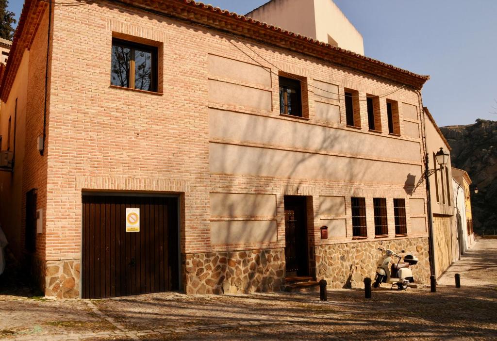 un bâtiment en briques avec deux portes et un homme assis à l'extérieur dans l'établissement CASA ANDAQUE con Parking y Patio en el Centro Histórico, à Tolède