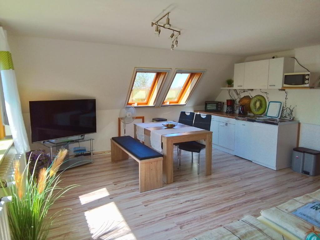 a living room with a table and a kitchen at Haus im Wind in Putbus