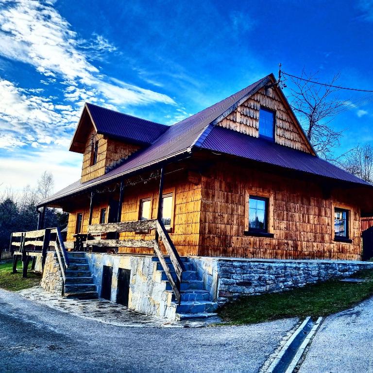 a large wooden house with stairs in front of it at Koronkowa Chatka w Beskidach in Istebna