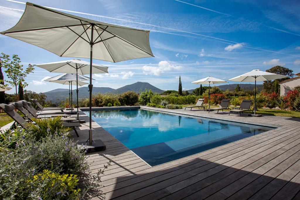 una piscina con sombrillas y sillas y una piscina en Domaine de l'auberderie Tropezienne en Plan-de-la-Tour