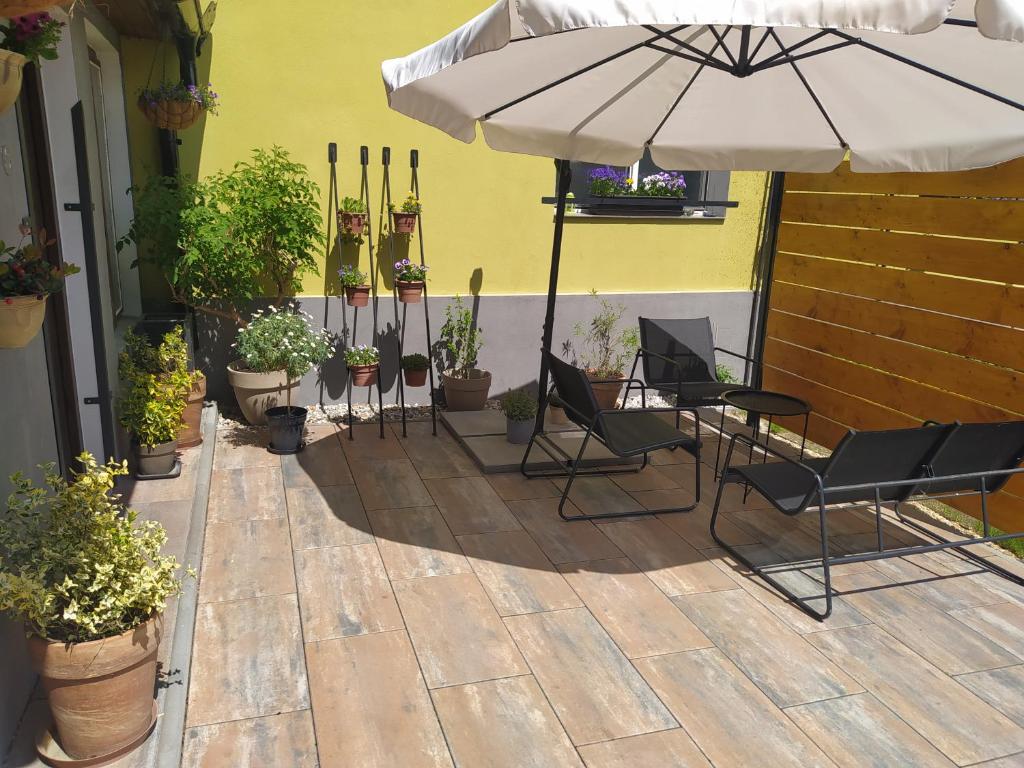a patio with chairs and an umbrella and potted plants at Ubytování Pohoda in Třeboň