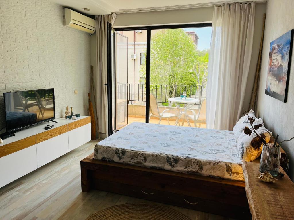 een slaapkamer met een bed, een tv en een balkon bij Relax studio in Sozopol