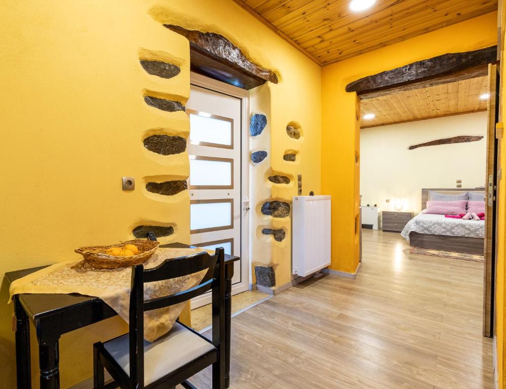a room with yellow walls and a table and a bed at Zois Stone House in Kántanos