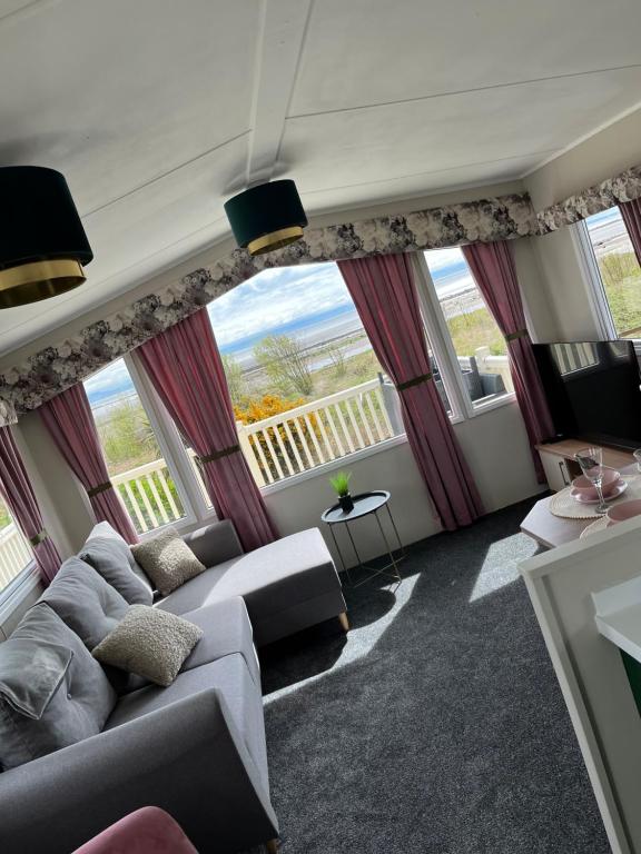 sala de estar con sofá y ventanas grandes en Marianne Bay - Southerness Caravan Park with Sea View - Pet Friendly en Mainsriddle