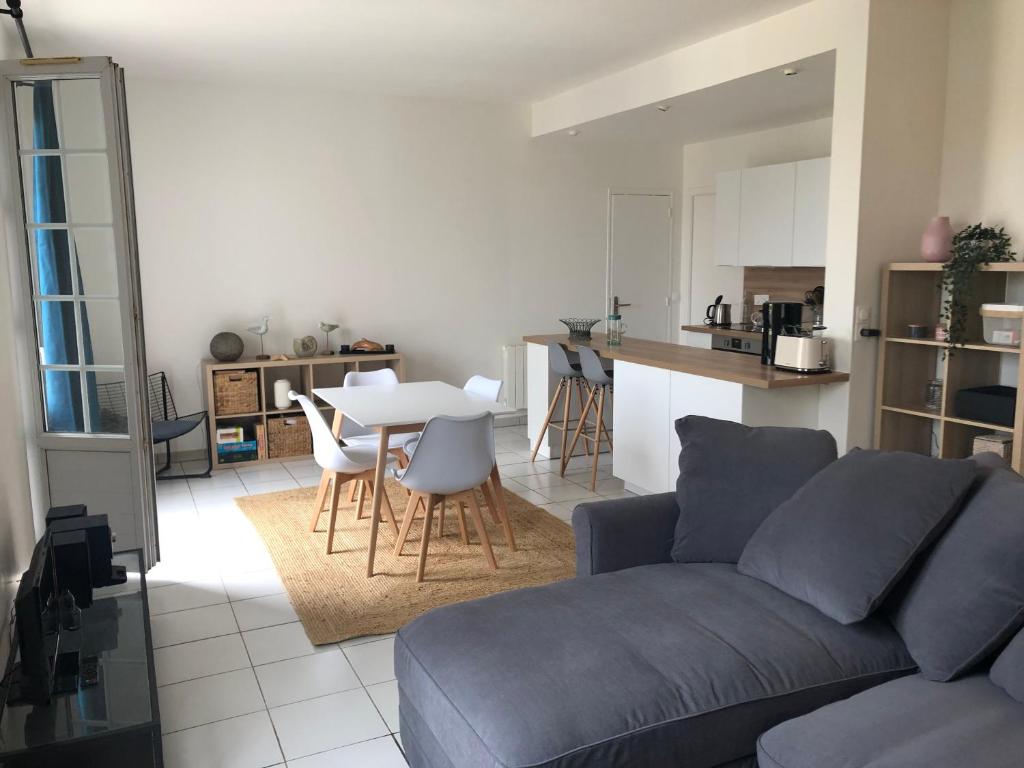 een woonkamer en een keuken met een bank en een tafel bij Le tennis garden in Villers-sur-Mer