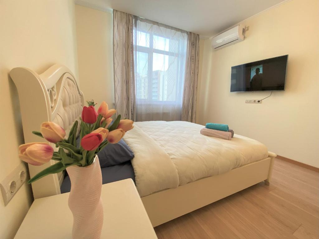 a bedroom with a bed and a vase of flowers on a table at FlatService Апартаменти в сучасному ЖК Parklend in Kyiv
