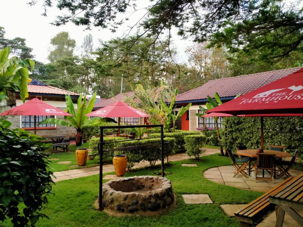 a garden with tables and chairs and umbrellas at The Farmhouse Inn in Nanyuki
