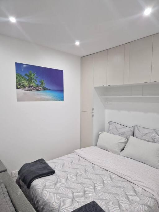 - une chambre blanche avec un lit orné d'une peinture murale dans l'établissement Joli studio calme contemporain CDG/PARC D'EXPO VILLEPINTE/PARIS, à Aulnay-sous-Bois