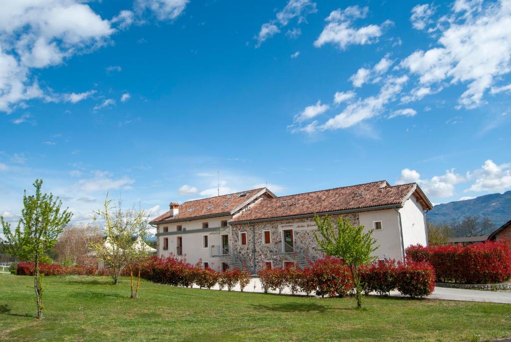 un grande edificio bianco con cespugli rossi e alberi di Agriturismo Antico Splendore a Pullir