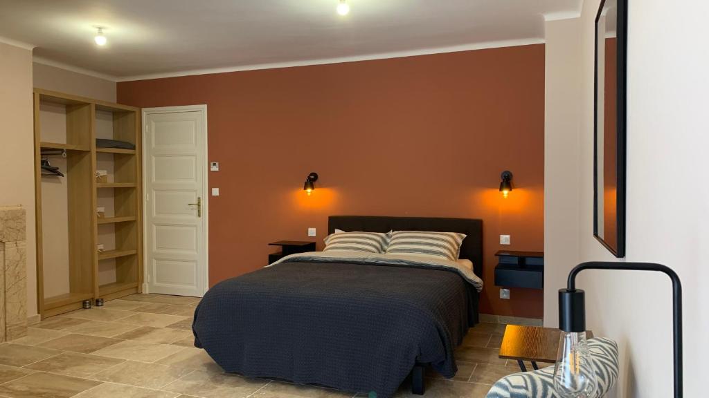 a bedroom with a bed with orange walls at Logis de la Foulerie in Bize-Minervois