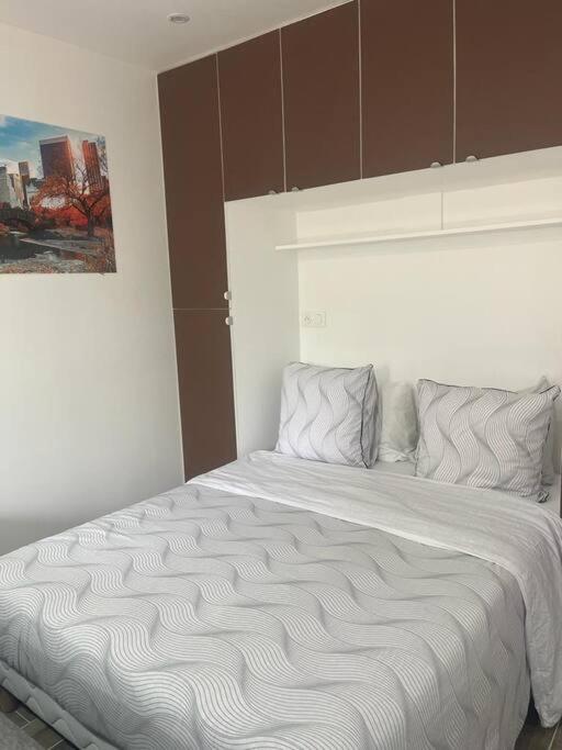 une chambre avec un grand lit blanc dans une pièce dans l'établissement JolyStudio indépendant CDG/PARC D'EXPO VILLEPINTE/PARIS, à Aulnay-sous-Bois