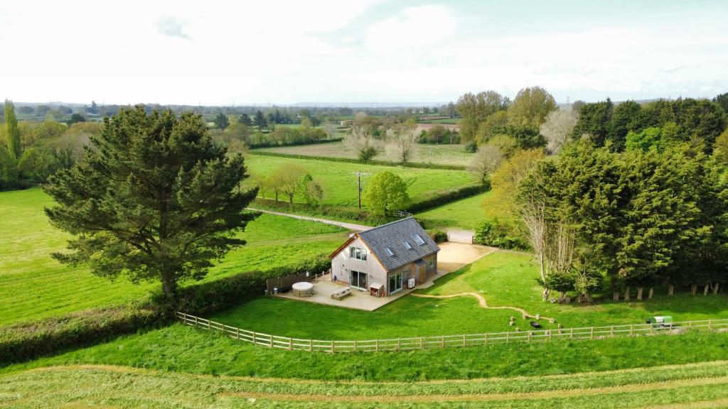 une vue aérienne sur une petite maison dans un champ dans l'établissement Deer Den timber clad cabin with hot tub, up private lane, à Cullompton