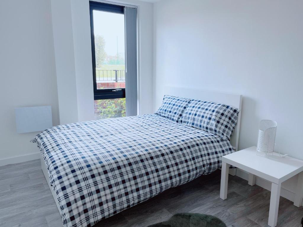 Una cama con una manta a cuadros y una mesa en una habitación en Modern House, en Mánchester
