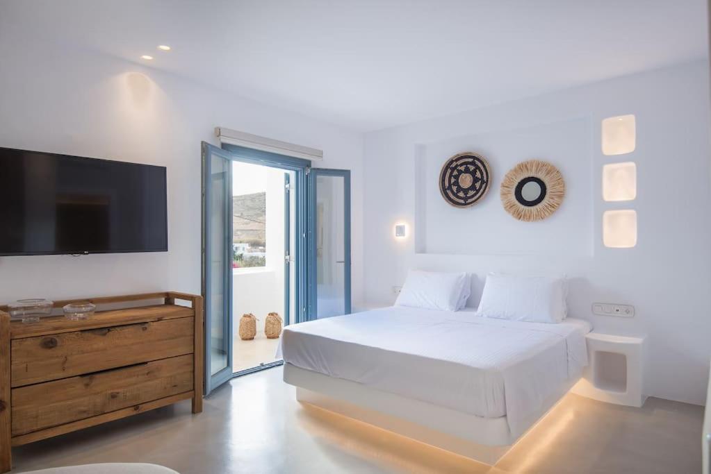 a white bedroom with a bed and a flat screen tv at ABA Ηospitalité Paros- The Luxury Suite, Naousa, Paros in Naousa