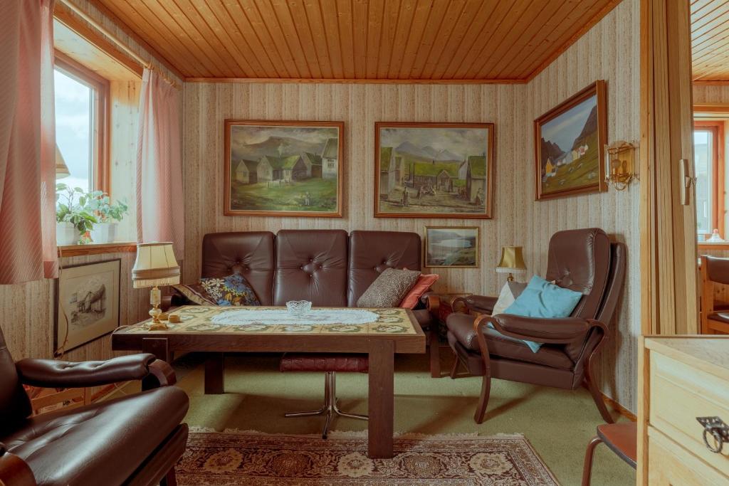 a living room with a couch and a table and chairs at 3-Bedroom Home in Eiði 