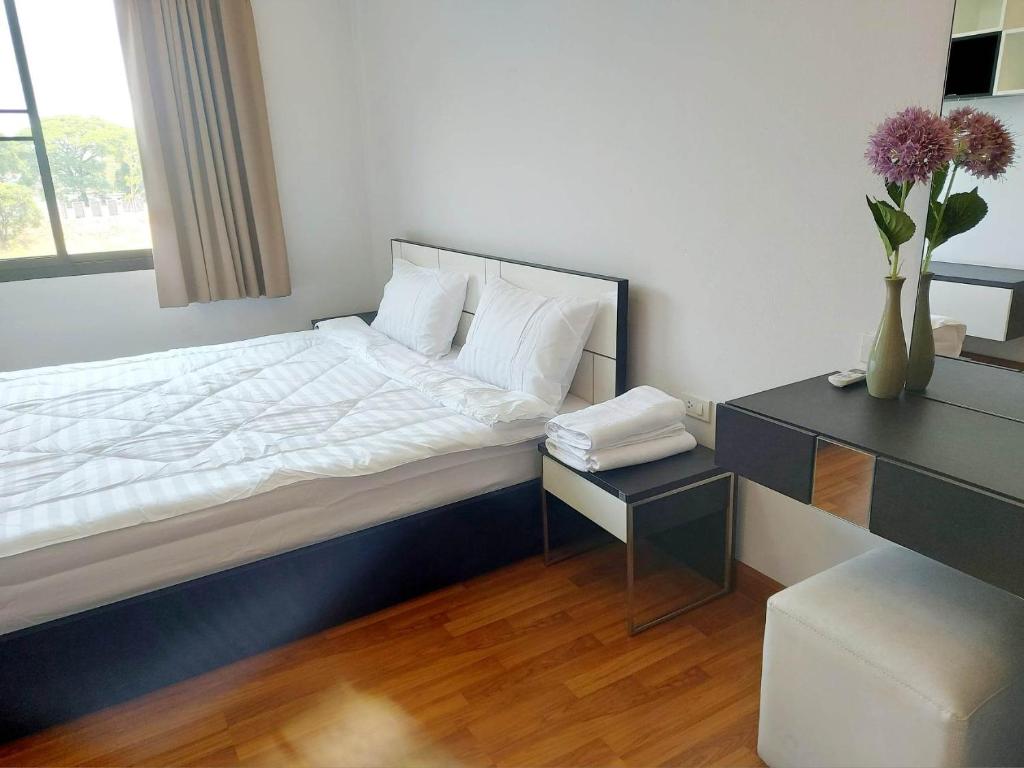 een slaapkamer met een bed en een tafel met een vaas met bloemen bij Cat Mama Penthouse Vtwin building A in Chiang Mai