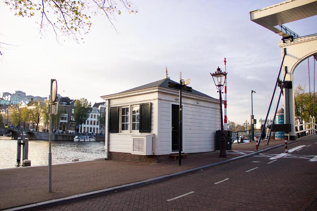 een klein wit gebouw aan de kant van een rivier bij SWEETS Walter Süskindbrug in Amsterdam