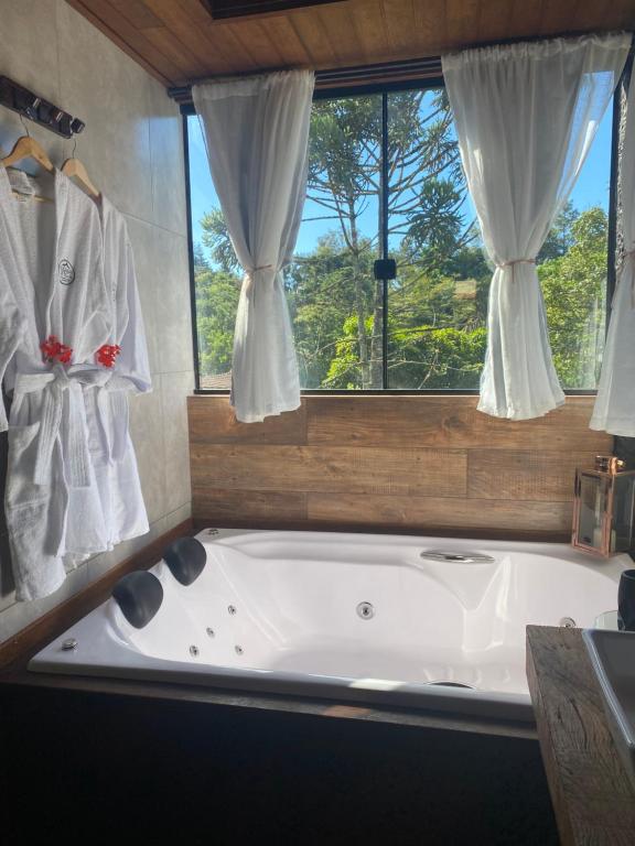 baño con bañera grande y ventana en Pousada do Figa, en Visconde De Maua