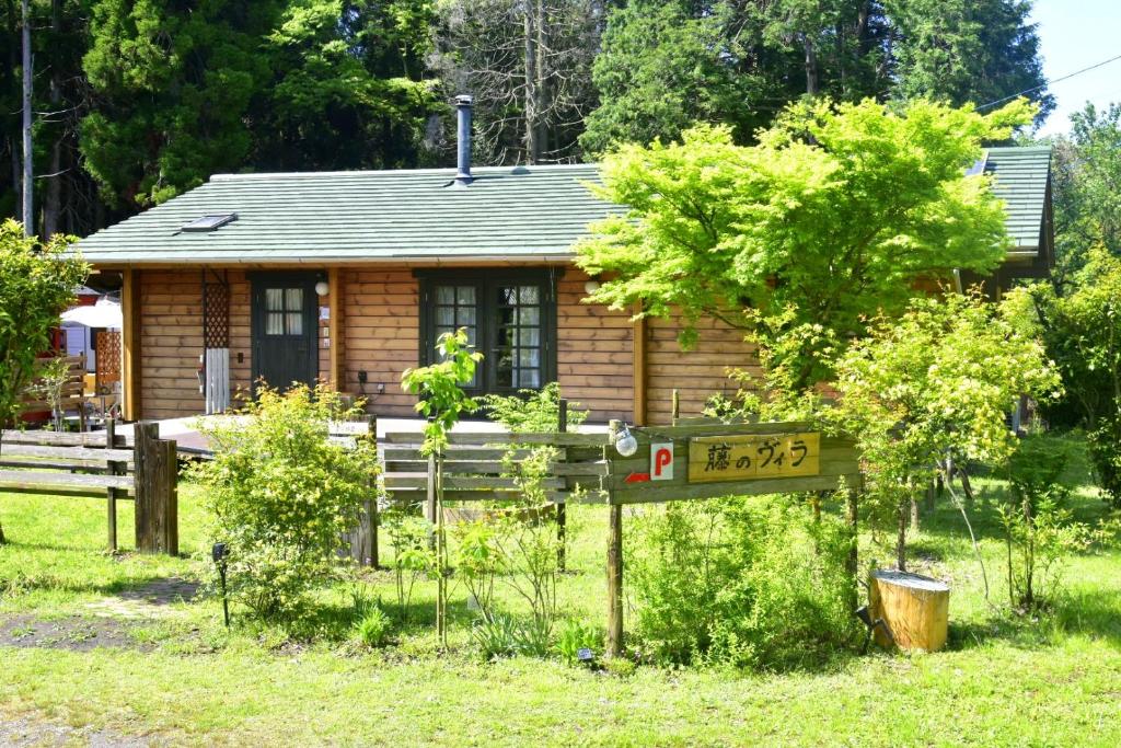 une petite cabane en rondins avec un panneau en face de celle-ci dans l'établissement 藤のヴィラ パイン棟 Check-out11時まで! Self Check-in, à Aso