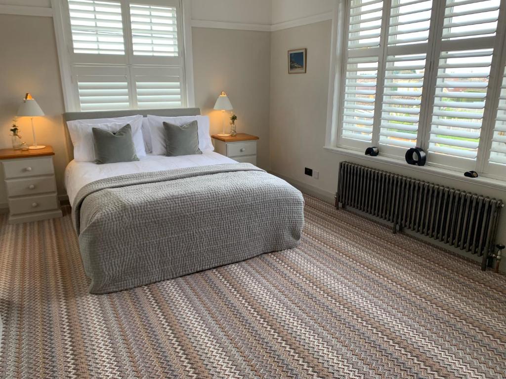 a bedroom with a large bed with two windows at The Old Bell in Grimston