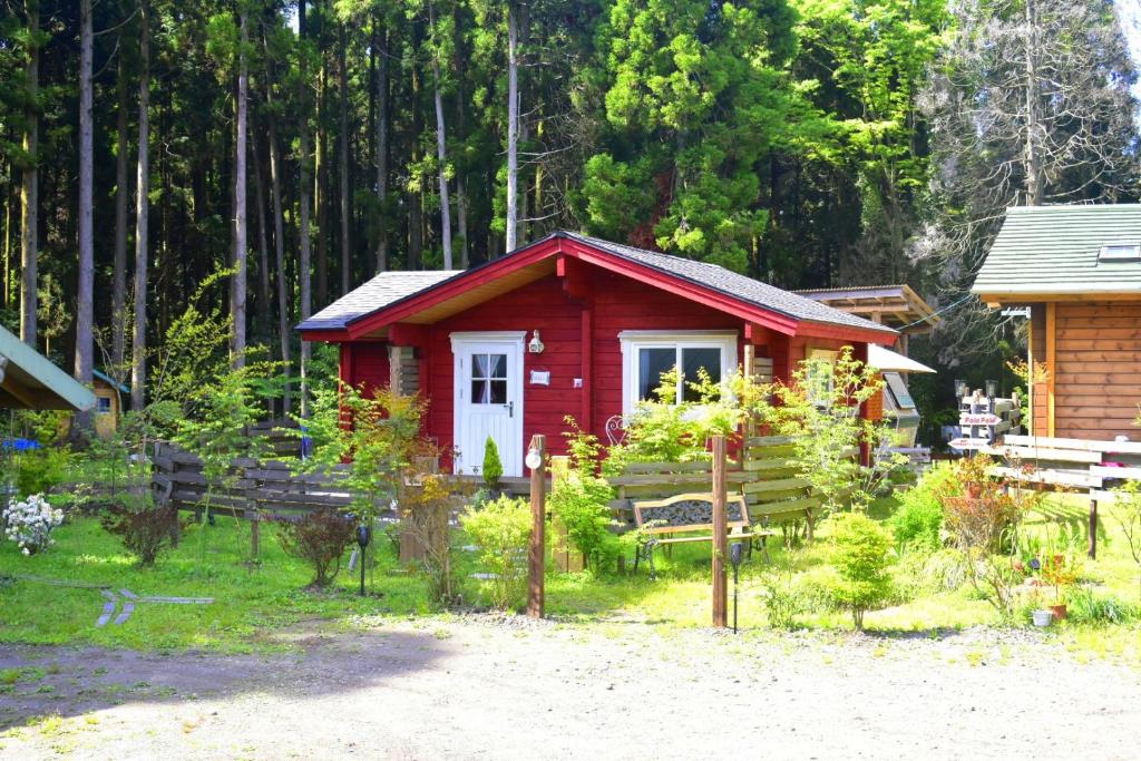una piccola cabina rossa in mezzo a un giardino di 藤のヴィラ チェリー棟 Self Check-in ad Aso
