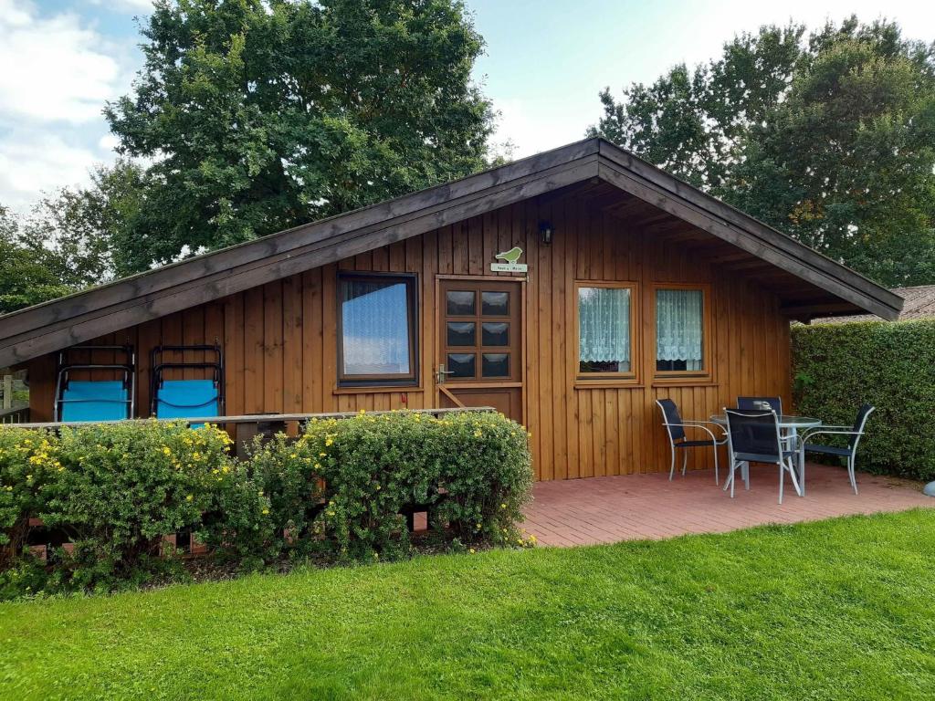 Cabaña de madera con mesa y sillas en una terraza en Landhof Kützin Ferienhaus 4 Meise, 