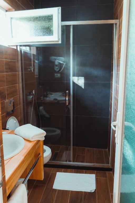 a bathroom with a shower with a toilet and a sink at Guesthouse Lord Byron in Tepelenë