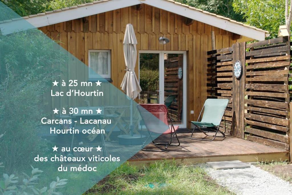 eine Holzhütte mit einem Sonnenschirm und 2 Stühlen in der Unterkunft La cabane in Saint-Laurent-de-Médoc