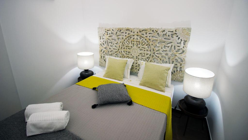 a bedroom with a bed with two lamps and a yellow at Casa do Marquês in Vidigueira