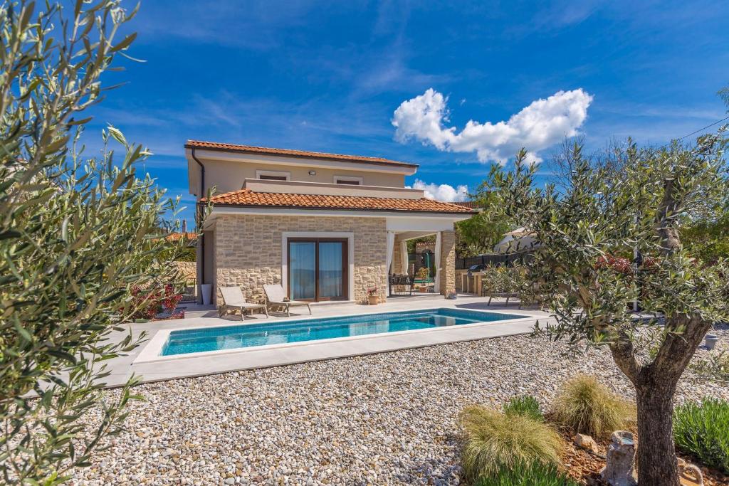a villa with a swimming pool and a house at Holiday house VILLA ANDRO in Pinezici