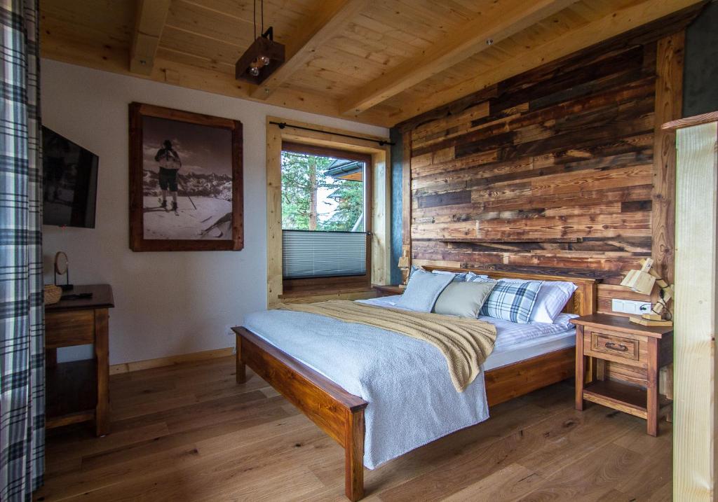 sypialnia z łóżkiem i drewnianą ścianą w obiekcie Stacja Murzasichle w Murzasichlu