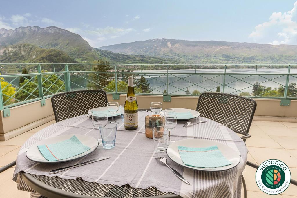 a table with a bottle of wine and glasses on a balcony at L'Hermitage, 4 appartements avec terrasse, vue lac, parking et PISCINE, LLA Selections by Location Lac Annecy in Talloires