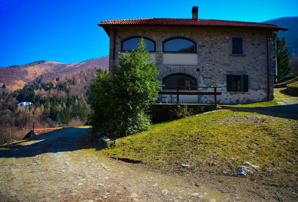 a house on a hill with a tree in front of it at Il Larice - Agriturismo Alpe del Ville San Primo by Wonderful Italy in Bellagio