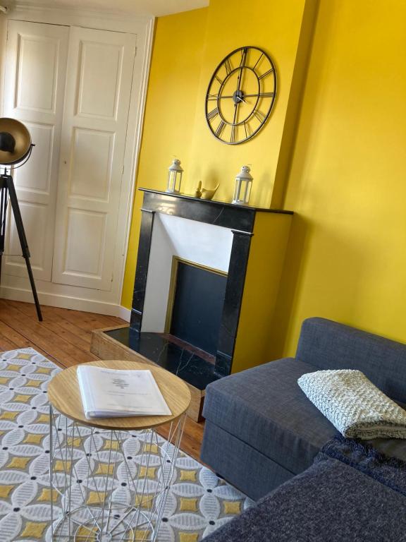 a living room with a fireplace and a clock on the wall at L'escale Granvillaise in Granville