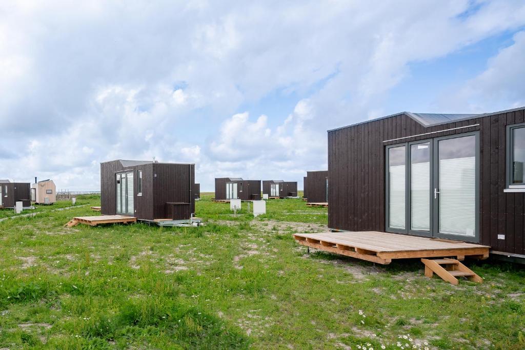 a row of black modular houses in a field at Tiny House Nature 4 Innenlage - Green Tiny Village Harlesiel in Carolinensiel