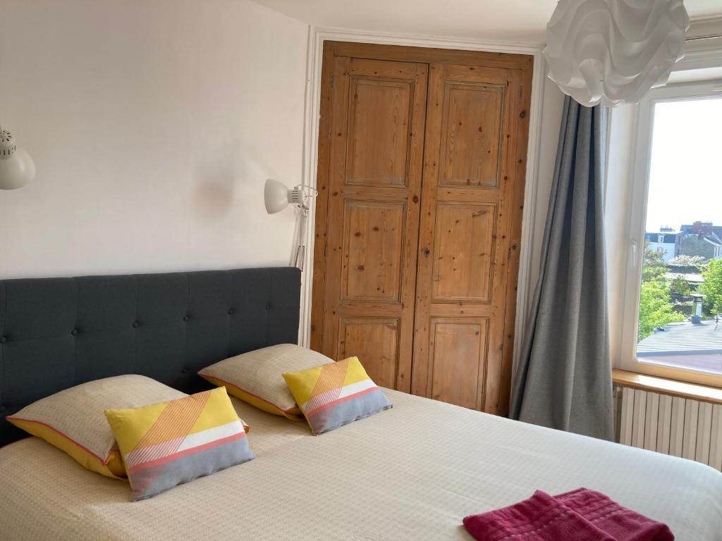 a bedroom with a bed with two pillows and a window at L'escale Granvillaise in Granville