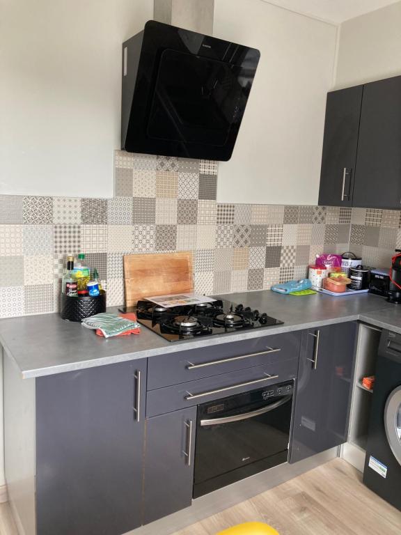 a kitchen with a stove and a tv on the wall at L'escale Granvillaise in Granville