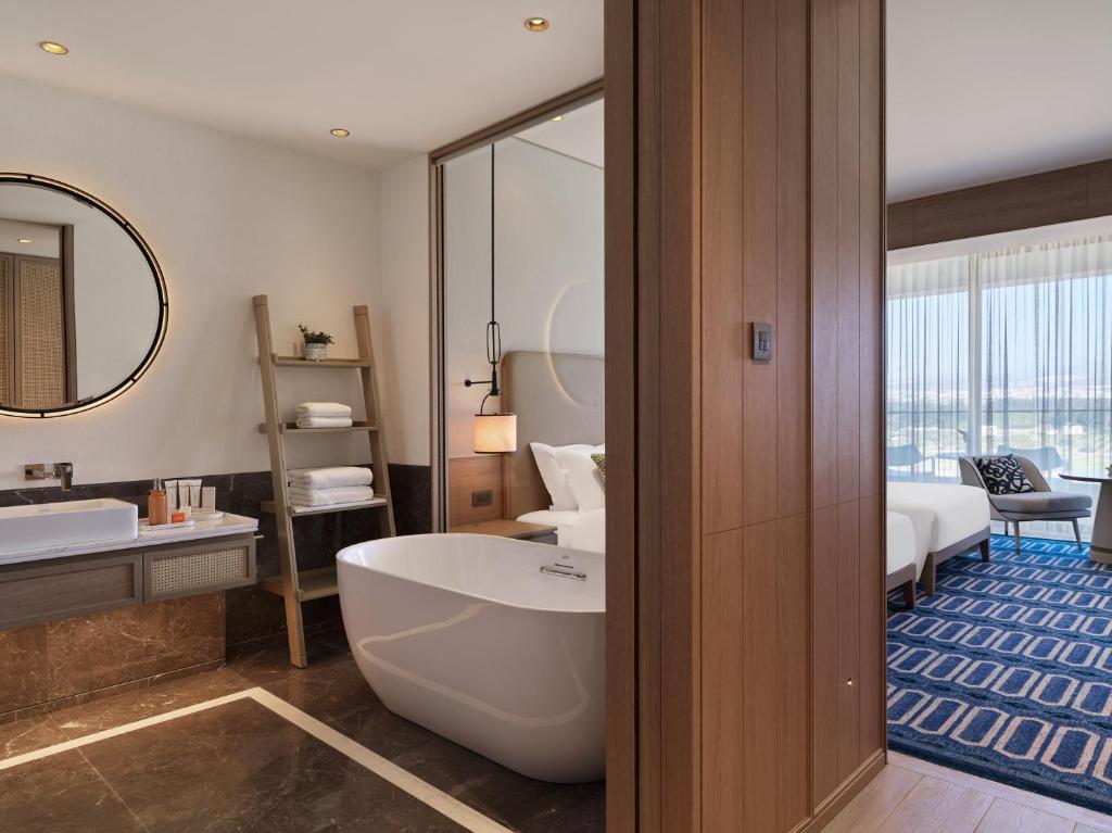 a bathroom with a bath tub and a bedroom at City of Dreams Mediterranean - Integrated Resort, Casino & Entertainment in Limassol