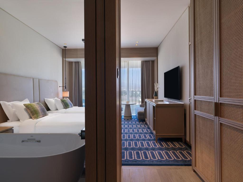 a hotel room with a bed and a tv and a tub at City of Dreams Mediterranean - Integrated Resort, Casino & Entertainment in Limassol
