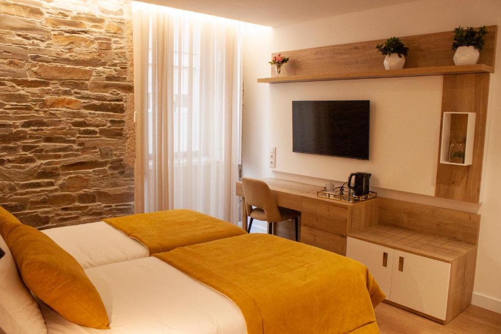 a bedroom with a bed and a desk with a television at Coração do Tua Hotel in Mirandela